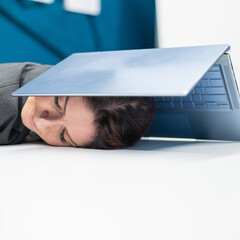 Exhausted business woman covered head with laptop. Tired female worker with a computer above her head.