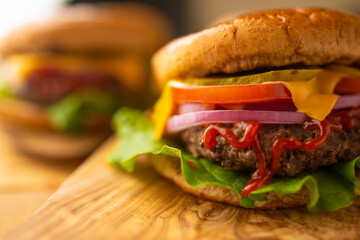 Burger for your dinner. Tasty fast food. Burger with cheese, tomato, onion. green salad and meat cutlet. Wooden background. Twins burger. Restaurants food