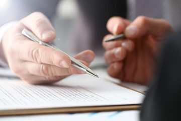 Male arm in suit and tie fill form clipped pad with silver pen closeup. Sign gesture read pact sale agent bank job make note loan credit mortgage investment finance executive chief legal teamwork law