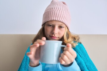 Cold season autumn winter, girl child sitting at home with mug of hot tea