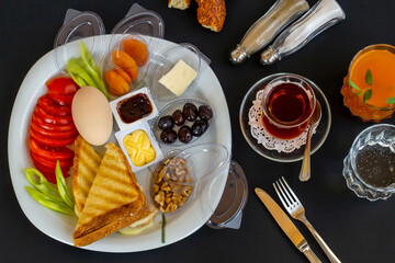 Traditional Turkish Breakfast Plate with boiled egg,orange juice and tea on black surface.Top view