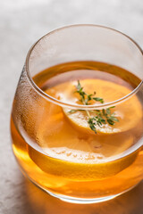 Hot tea in a glass with lemon and thyme close-up, side light. Autumn and winter traditional drinks.