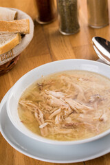 Bowl of chicken soup. Chicken soup in a white plate on wooden table.