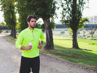 Young bearded man in yellow sportswear running in the park. Lifestyle.