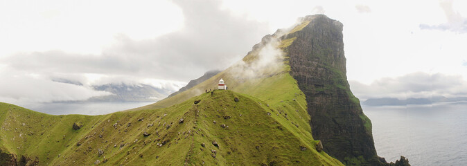 Kallur Lighthouse on Kalsoy Island in a green grass landscape on the Faroe Islands, Denmark.