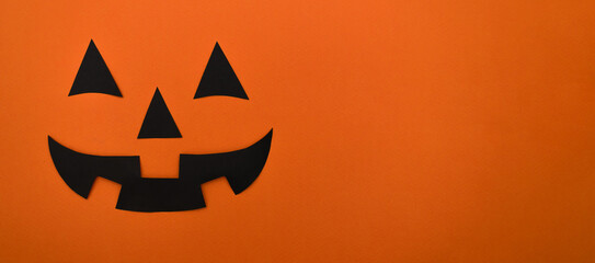 Black eyes,nose and mouth of black paper on an orange background.Happy Halloween concept.Copy space for text	

