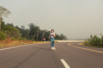 Obraz premium Woman running on the road. Jungle landscape. Concept of health and sport.