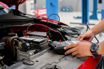 A mechanic uses a device to check the voltage of the car battery.