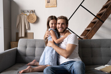 Obraz premium happy father and daughter hugging and sitting on sofa