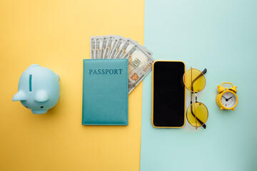 Save up for travelling. Travel planning with piggy bank, smartphone, sunglasses and passport with money on colorful background.