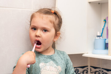 Little girl brushes her teeth in the morning in the bathroom