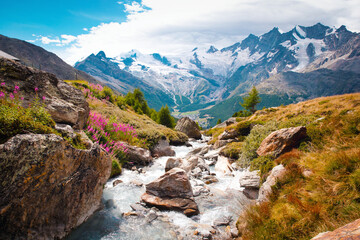 Beautiful mountain landscape with stream near Alps, Switzerland in the summer in blue sky