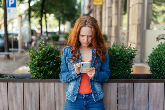 Puzzled young woman staring at her mobile phone