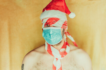 man with santa claus hat with blue hygienic mask, on yellow background
