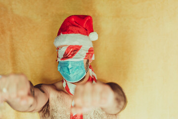 man with santa claus hat with blue hygienic mask, with closed fists
