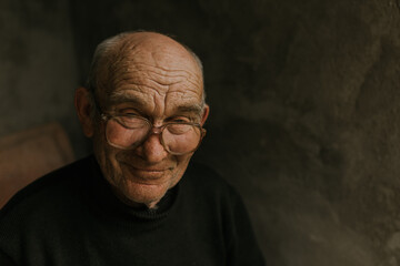 Pensive old man in glasses with gray hair looks away. wrinkles. wisdom. against a dark gray texture wall. bald head. in a knitted sweater. Portrait.