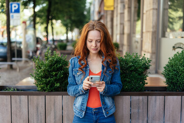 Young redhead woman reading an sms on her phone