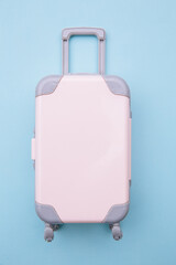 Mini travel luggage suitcase on blue background. Travel, summer vacation or tourism concept.