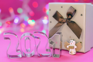 New year 2021 and Christmas gift box with bow with colorful lights on pink background