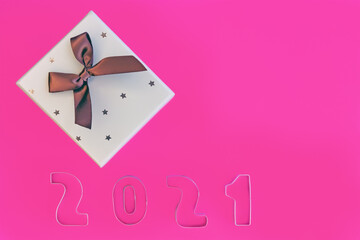Christmas gift box with bow with the numbers 2021 on pink background