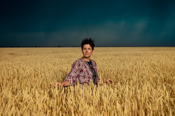 Naklejka na ściany i meble girl in a wheat field before a thunderstorm