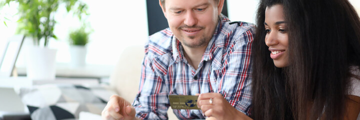 Portrait of beautiful afro-american woman smiling and holding credit card. Middle-aged man using...