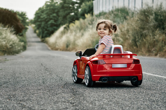 Fototapeta A girl riding a toy car