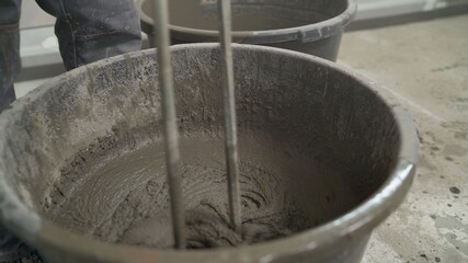 The mortar is mixed in a bucket. Floor repair. Mixing of building floor mortar. mixing cement in the bucket mixer with the trowel at the side work, Construction work