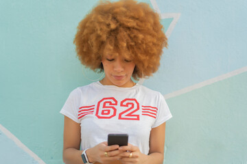 woman with afro hair using her smartphone