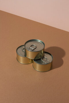 Bunch of sealed tin cans with preserved food placed on brown surface