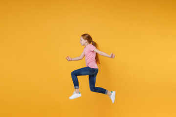 Fototapeta na wymiar Full length children studio portrait side view of funny little ginger redhead kid girl 12-13 years old wearing pink casual t-shirt posing jumping like running isolated on yellow color wall background.