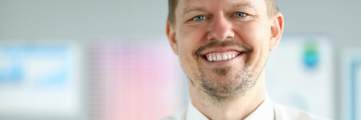 Close-up of smiling middle-aged businessman wearing presentable suit. Copy space in left side. Macro shot of happy employee with shining smile. Business company concept