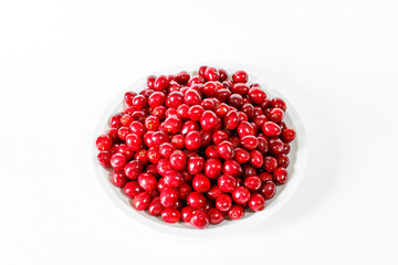Red cherries on a white plate on a white background