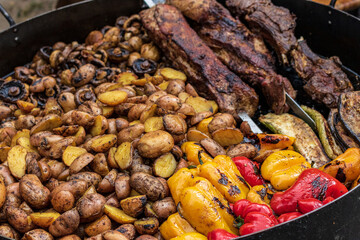 Healthy street food to go - potatoes, mushrooms, eggplants, meats, bell peppers, and red tomatoes. Delicious food cooked over an open fire, which is offered at a street food fair, event, festival.