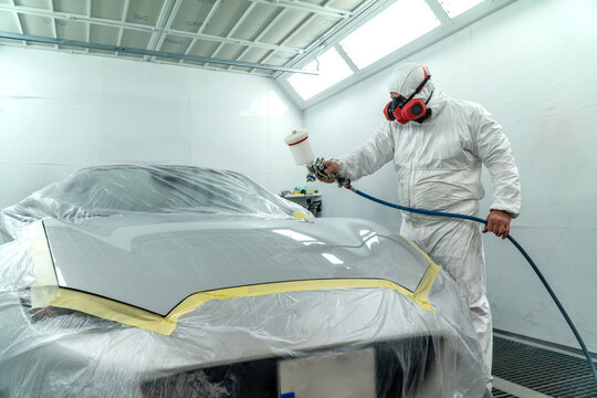 Automobile painting. Car painter with gun in chamber. Spray operation. 