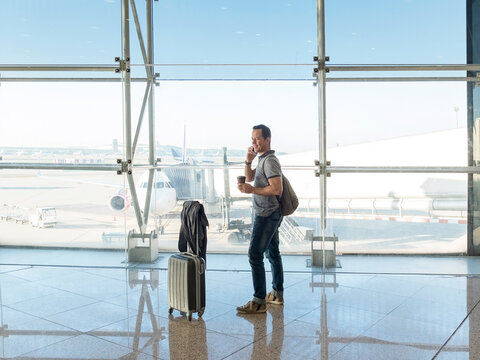 young woman with suitcase talking on phone while waiting for flight