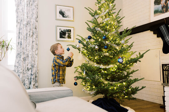 Little boy putting ornaments on his Christmas tree