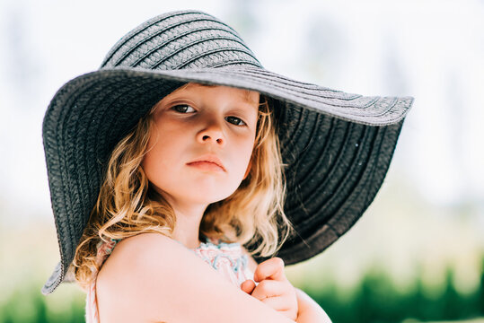 portrait of a sassy young girl staring at the camera with a sun hat on