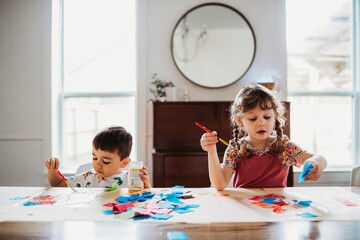 Brother and sister creating art together at home in spring