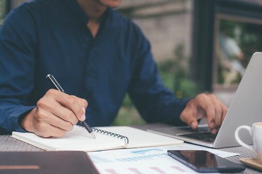 Closeup businessman writing hand and using computer.