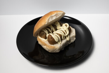 Dutch snack broodje frikandel met mayonaise sauce. Deep fried snacks The Netherlands. Frikandel on a white bun.