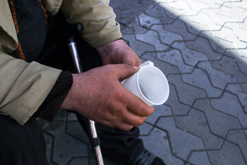 beggar holding a mug for money