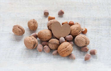 Cardboard heart among nuts on a white wooden table Valentine's card