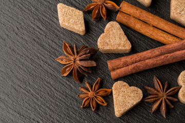 Anise, cinnamon and pieces of sugar on a black stone background close-up. Spice concept