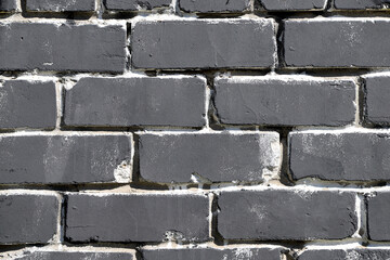 Texture of a brick wall coated with dark gray paint