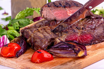 Marble beef rib eye steak with fried tomatoes and onions on a wooden Board