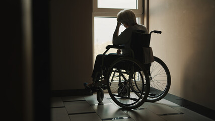 lonely senior woman looking through the window of the nursing home. Mental health affected during the quarantine. High quality photo