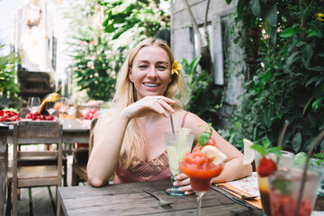 Fototapeta na wymiar Cheerful woman enjoying cocktail in outdoor cafe