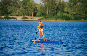Young beautiful woman in a bikini on a SUP board in the river