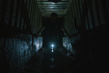  The guy in the underground tunnel inside old sewer shaft - obrazy, fototapety, plakaty
